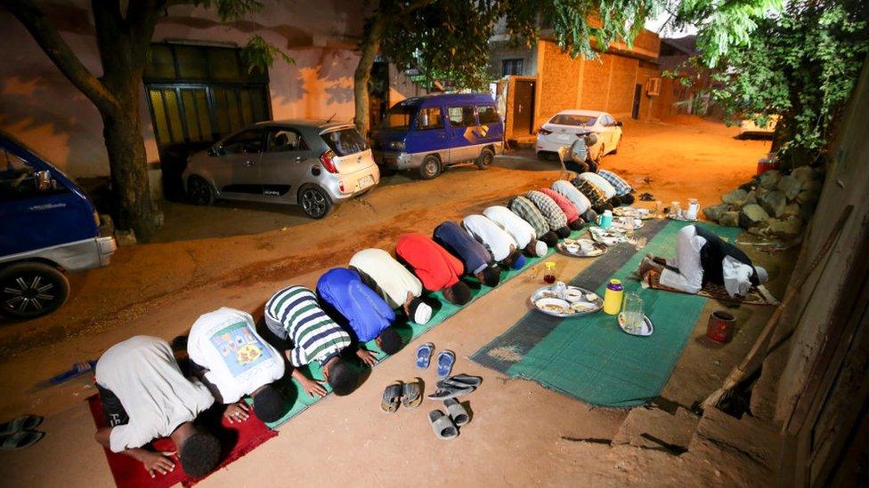 Sudanese men gather in prayers in a street in the capital Khartoum after breaking their fast during the Muslim holy month of Ramadan on April 25, 2020, amid a curfew due to the COVID-19 coronavirus pandemic.