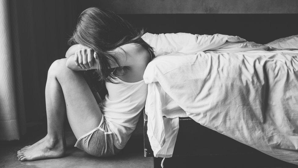 Portrait of depressed woman sitting alone on the floor in the bedroom