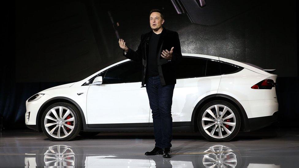 Elon Musk speaks in front of a Tesla SUV