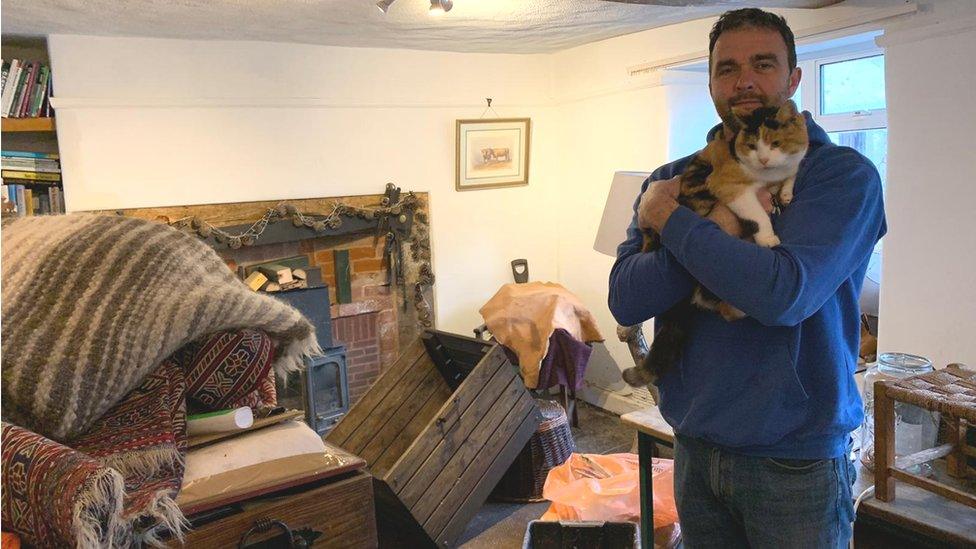 Griff Wyatt surveys the damage inside his home, while holding one of the family's cats