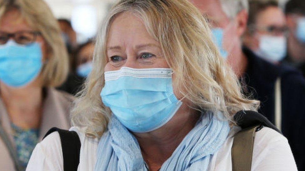 An Australian woman wearing a mask queues at Sydney Airport to board a plane to New Zealand