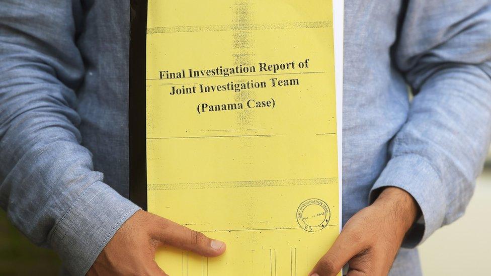 A Pakistani journalist poses for a photograph with a copy of a corruption report released by a Joint Investigation Team (JIT) in Islamabad on 12 July 2017