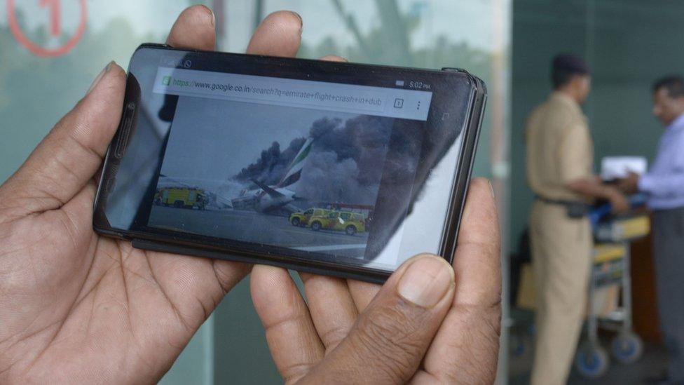 Man watching images of a plane crash on a mobile phone