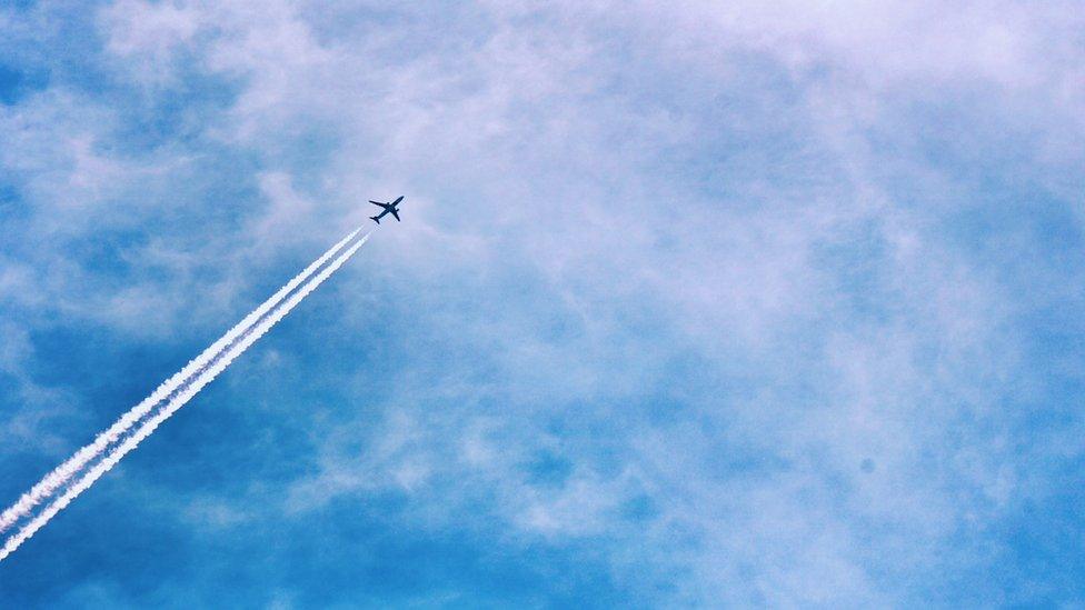 plane flying with air vapours behind