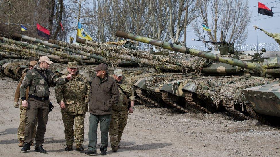 Ukrainian officers walk past a tank line from the volunteer Azov battalion (6 April)