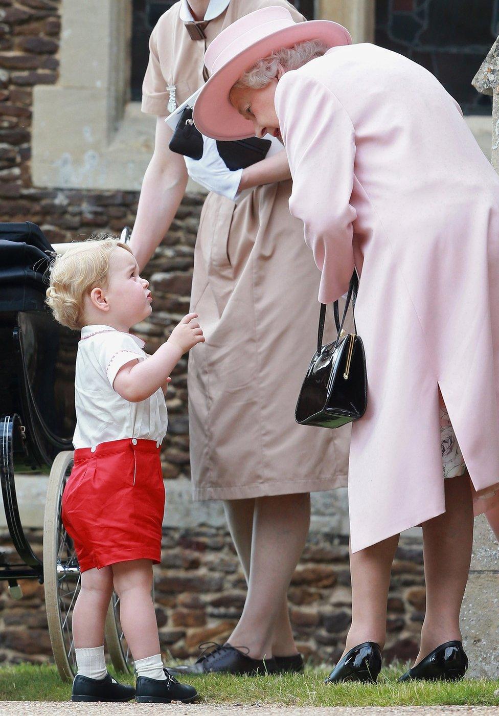 Prince George getting his grandmother Queen Elizabeth II attention at the christening of his sister Princess Charlotte.