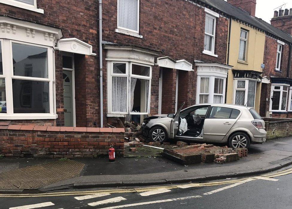 Car crashed into front of a house with wall rubble surrounding the vehicle