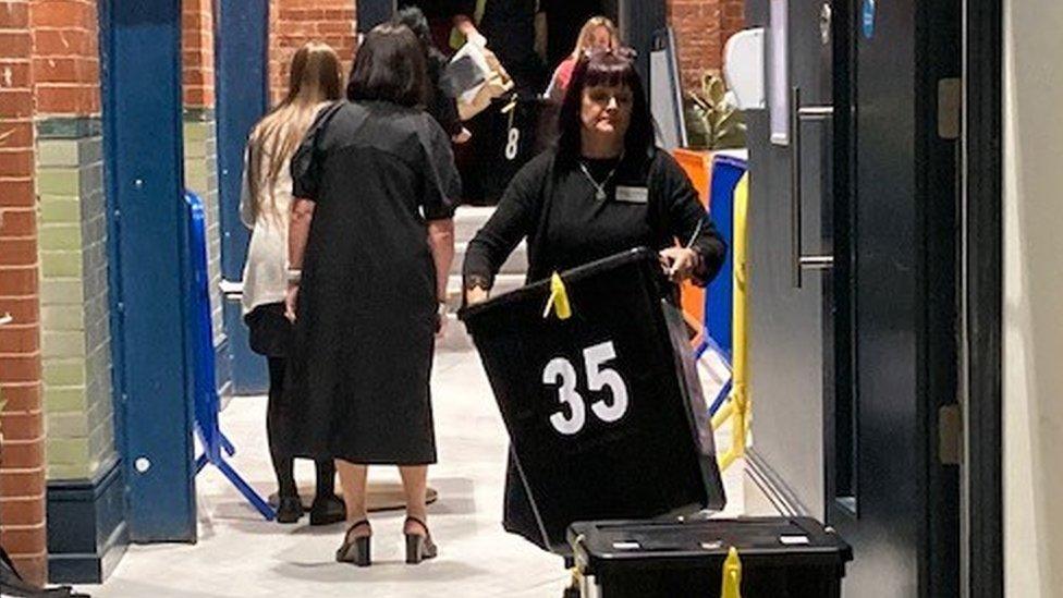 Woman carrying black ballot boxes