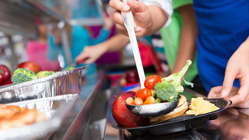 Close up of vegetables; students choosing food in school cafeteria - stock photo