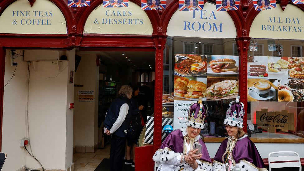 Royal fans dressed in royal-themed costumes sit outside a bar while waiting for the Coronation concert at Windsor Castle