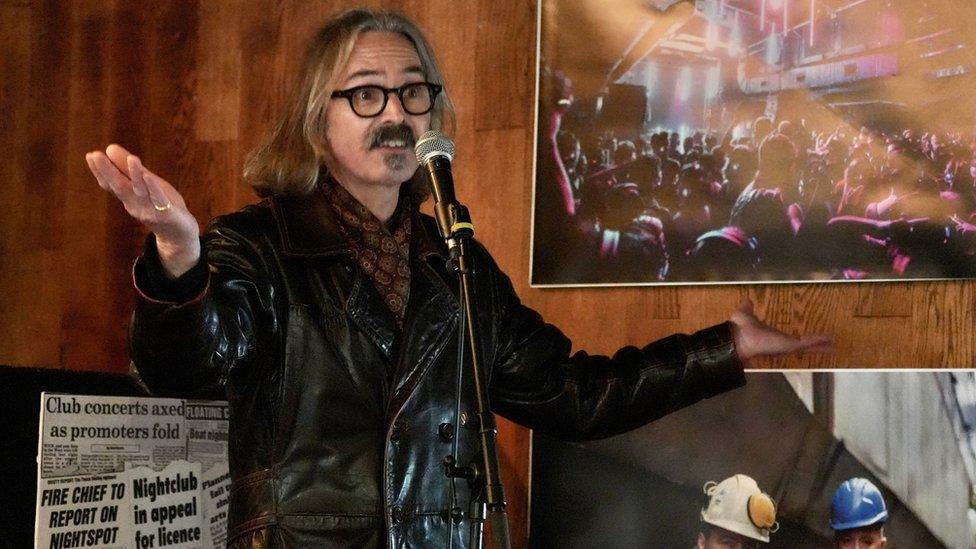 A man with a beard and glasses gives a speech on board Thekla in Bristol