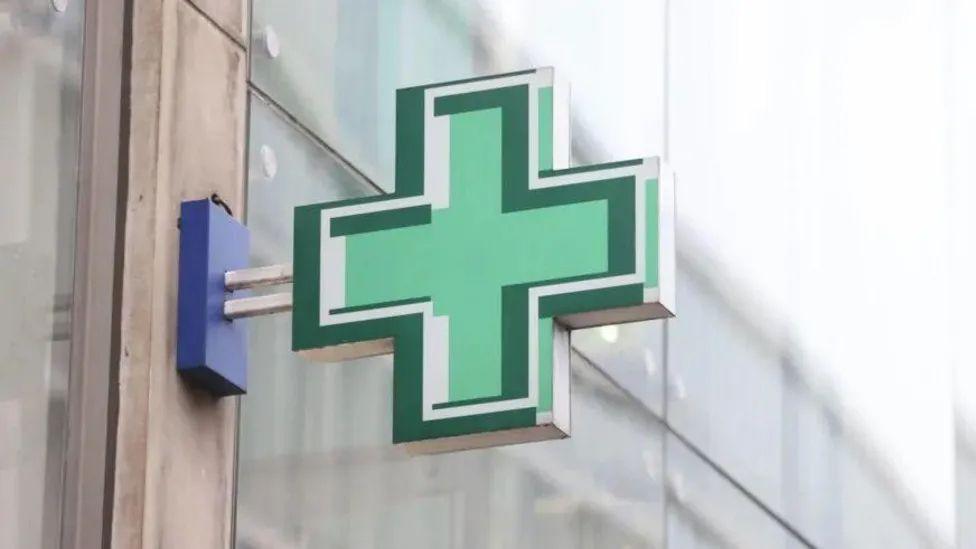 Green cross sign outside pharmacy window