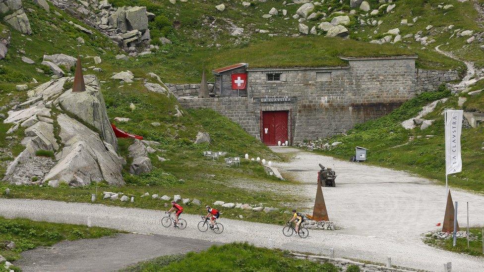 Cyclists ride past the Hotel La Claustra