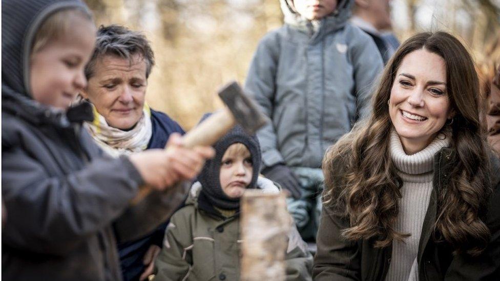 Duchess watches as boy chops wood