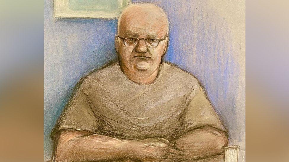 Court artist's image of Steve Wright wearing glasses and a T-shirt with his arms folded at a table during his appearance at Ipswich Magistrates' Court in June 2024