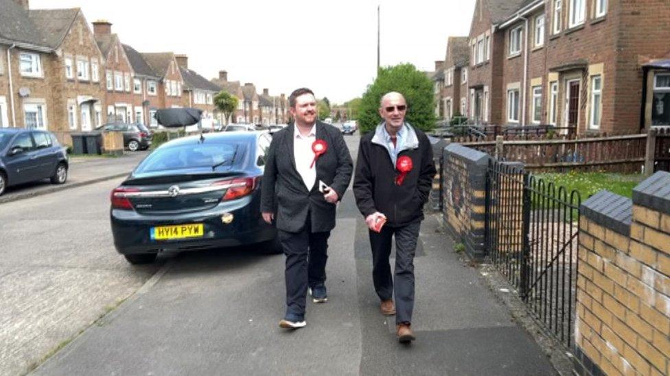 Terry Pullen and a fellow volunteer walking along a street with houses either side