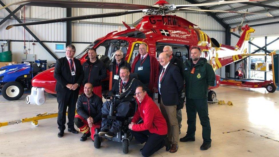 Team stood in front of a helicopter