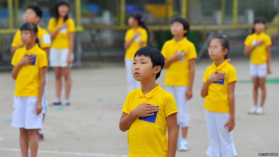 South Korean schoolchildren stand to attention during their national anthem