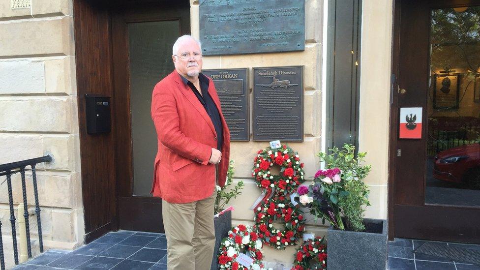 Anthony Kozlowski stands on the steps of the Sikorski Polish club in Glasgow, in front of memorial plaques