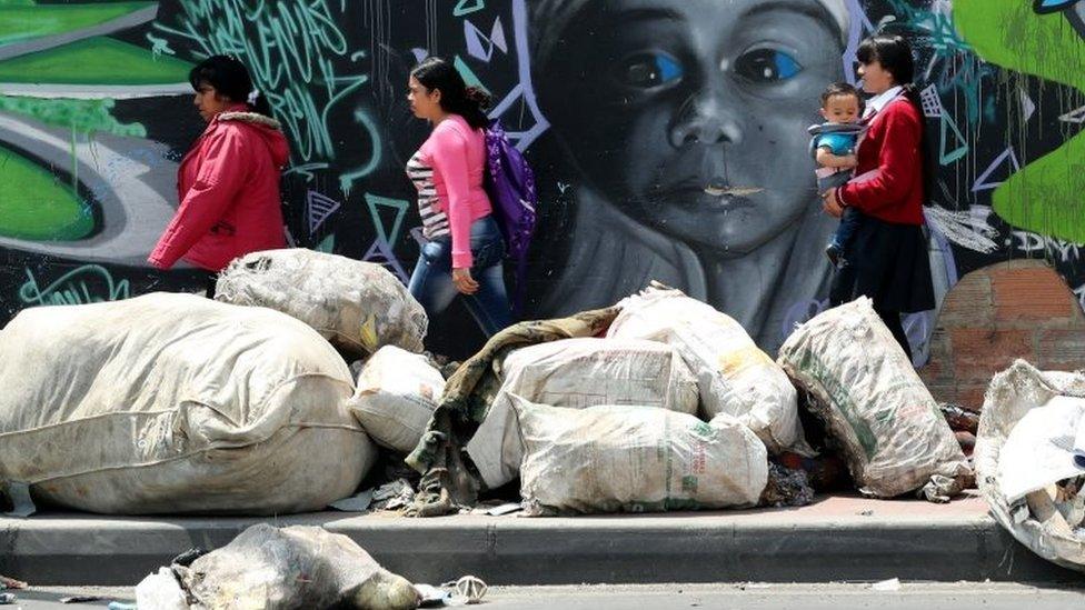 Pedestrians walk in the middle of garbage bags in Bogota, Colombia, 07 February 2018.