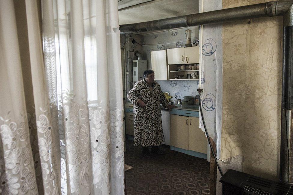 A woman stands in her kitchen