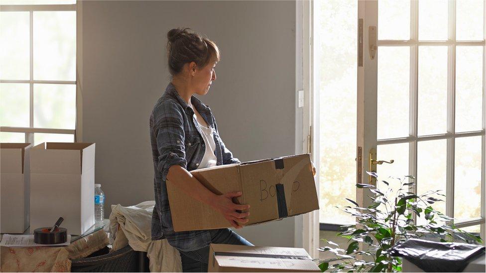 Woman carrying boxes into home