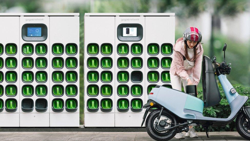 The owner of a Gogoro motorbike changing its battery