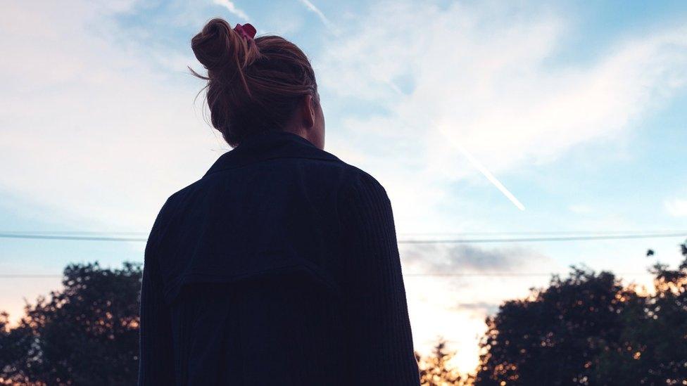 silhouette of a young woman looking at sunset