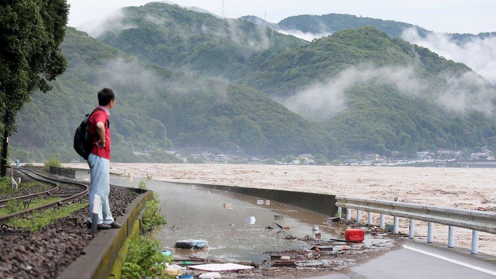 A man looks at the overflowing Kuma river in Yatsushiro, Kumamoto prefecture, 4 July