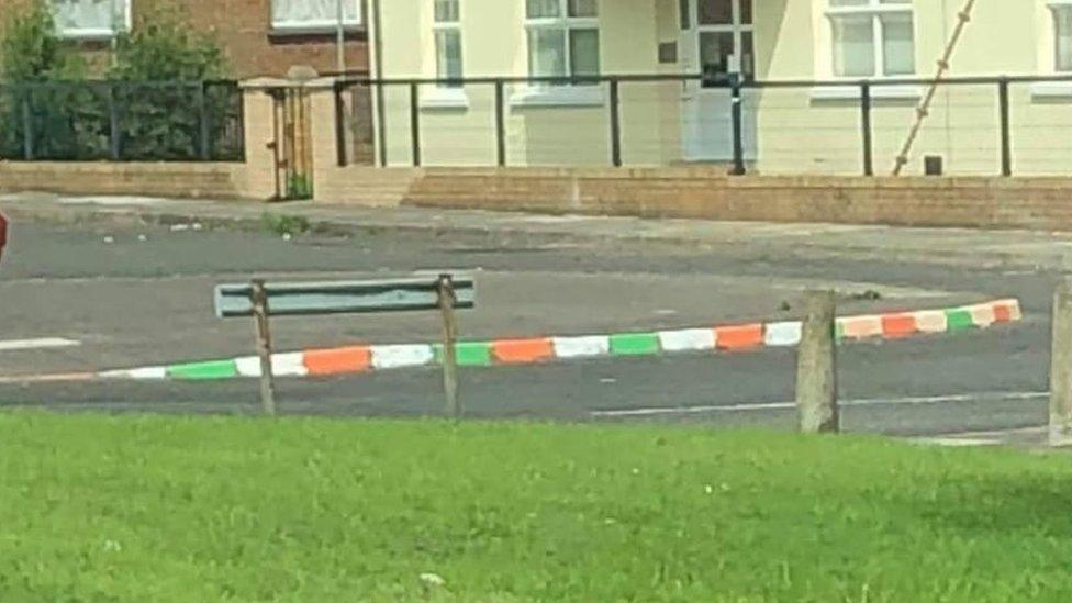 Kerbs in Limavady graffitied with green, white and orange paint.