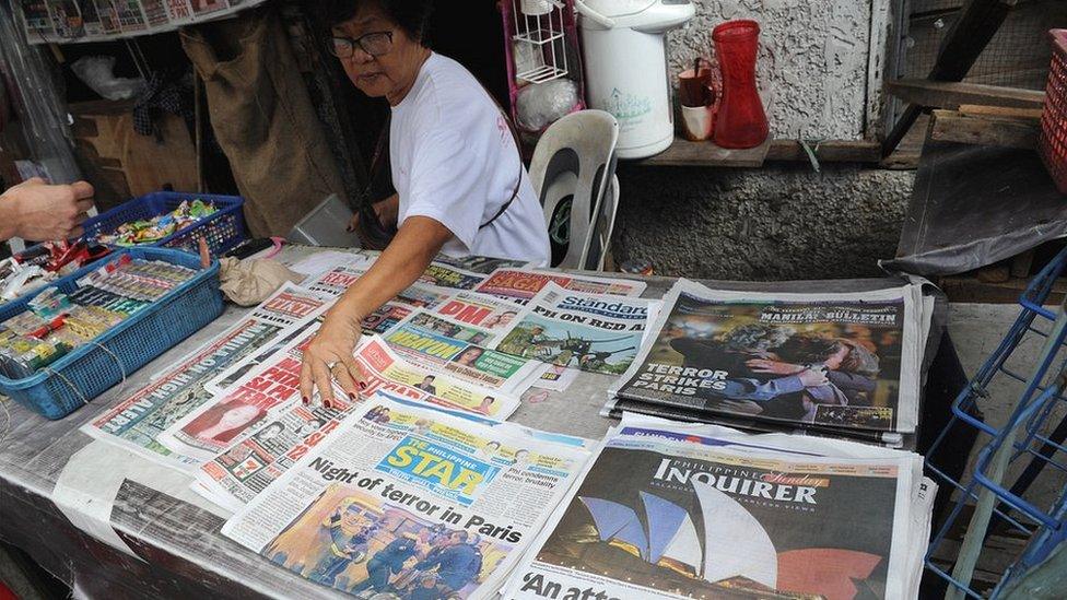 A woman sells newspapers with photos headlines of the Paris attacks in Manila on November 15, 2015