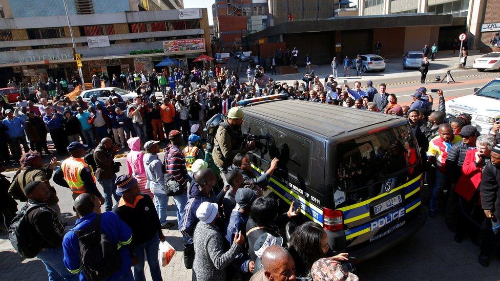 Journalists crowd around a van believed to be carrying Olympic and Paralympic track star Oscar Pistorius after his sentencing in Pretoria, South Africa on 6 July