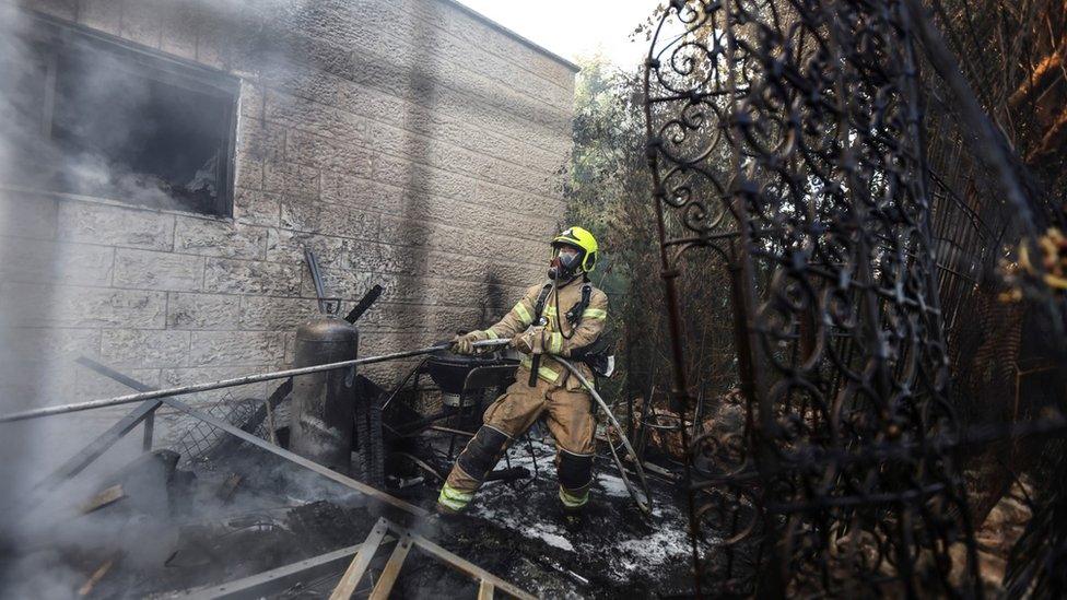 A firefighter works inside the Israeli village of Givat Yearim during a wildfire (16 August 2021)