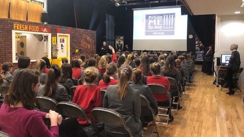 Presentation in a school hall with children watching the big screen of information