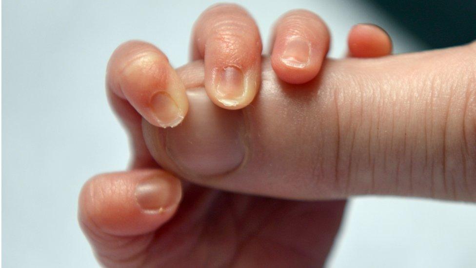 Baby holding mother's finger