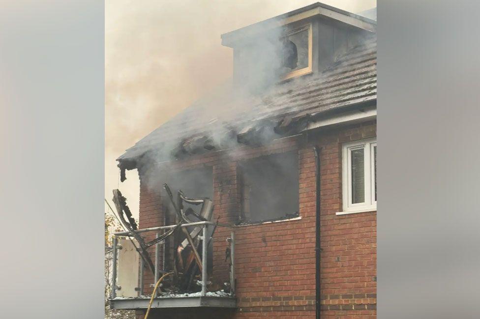 Handout from the LFB showing the house's burnt roof and smoke coming out of broken windows and debris falling off a balcony. 