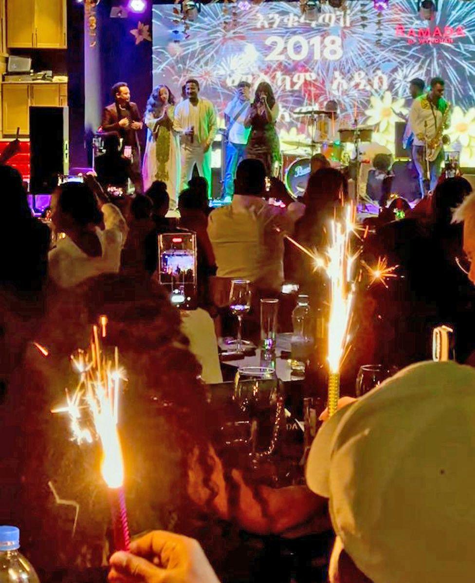 A band welcomes in the New Year on stage at a venue in Addis Ababa. Behind them is a picture of fire works with the year 2018 on it. People in the audience can be seen holding sparklers - Thursday 11 September 2025.