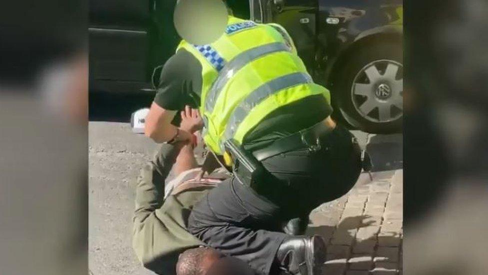 Still from a video showing a policeman appearing to kneel on a black man's neck during an arrest