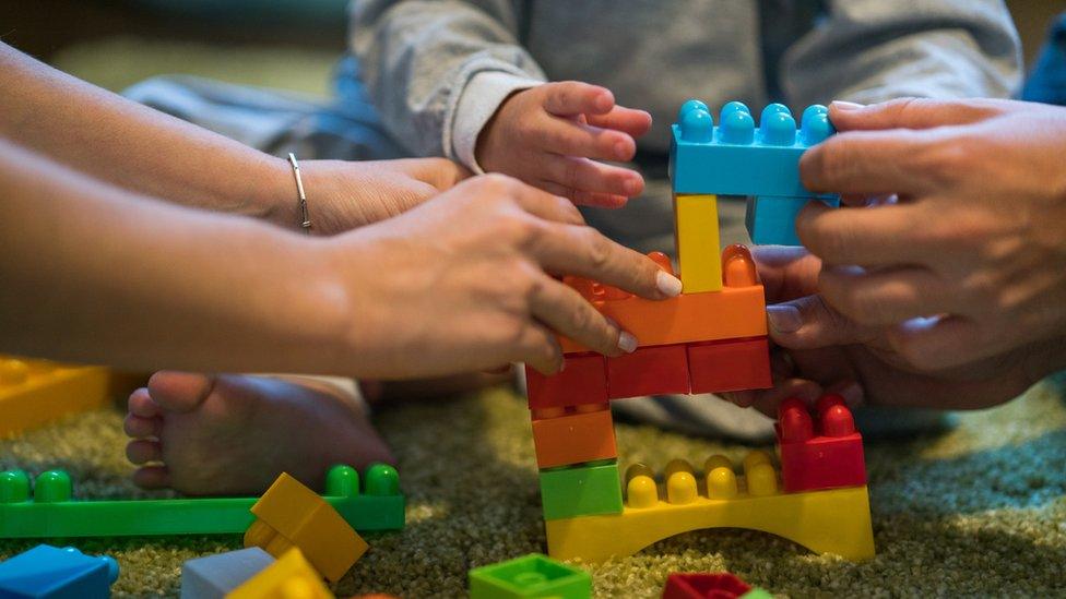 Man woman and child playing with plastic blocks