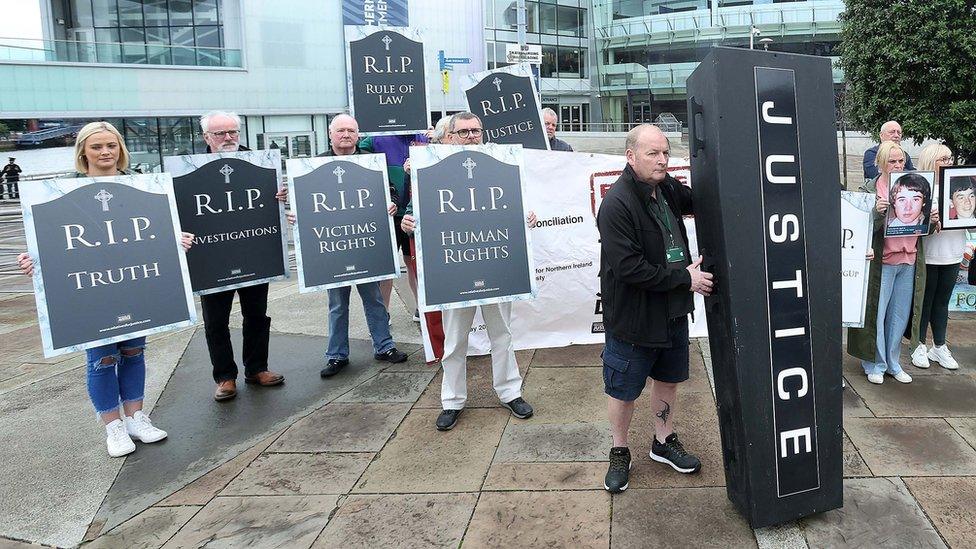 People hold signs reading R.I.P. truth, R.I.P investigations, R.I.P victims' rights and R.I.P human rights