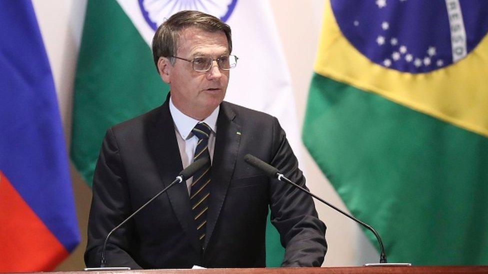 Bolsonaro standing in front of brazil flags