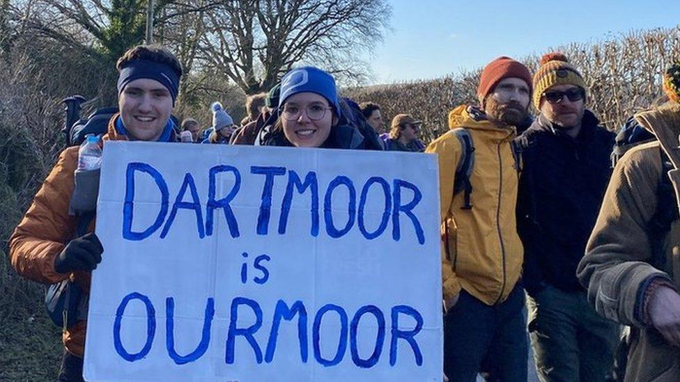 Young couple hold a sign that says "Dartmoor is Our Moor"