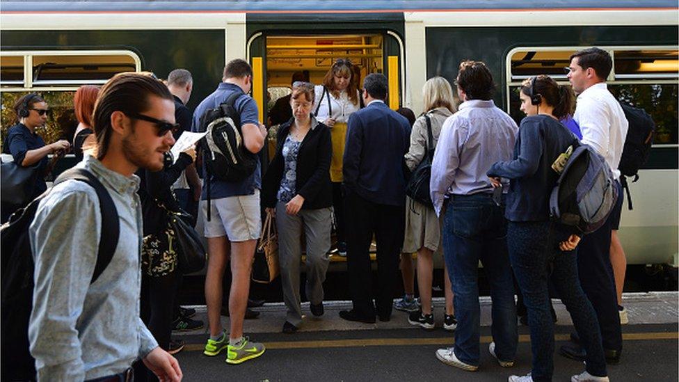 People disembark and wait to board a train on the hugely-reduced Southern rail service