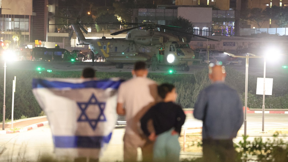 People look on as an Israeli army helicopter carrying hostages who were held by Hamas in Gaza, lands at the helipad of the Schneider-Children's Medical Center in Petah Tikva, Israel