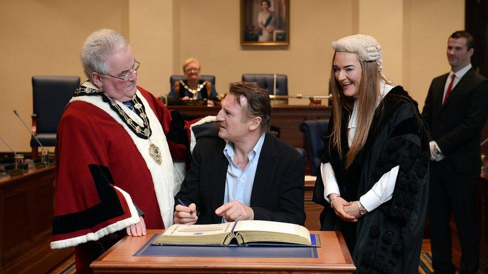Liam Neeson signs the book of burgesses confirmed his freedom of Ballymena award