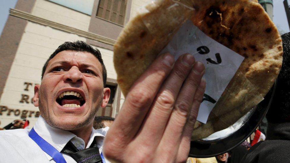 A man gestures with a piece of bread during a protest, to demand the government to offer unemployed graduates jobs, in front of the parliament headquarters in Cairo, 27 March 2016, where Egyptian Prime Minister Sherif Ismail was speaking.