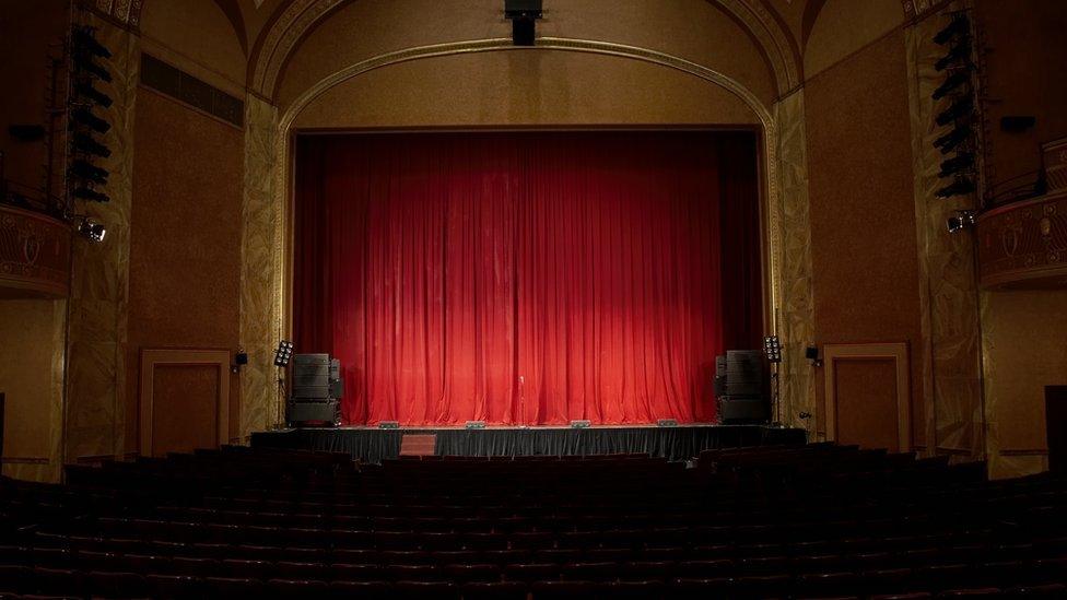 A view of a red curtain on the stage of an empty theatre