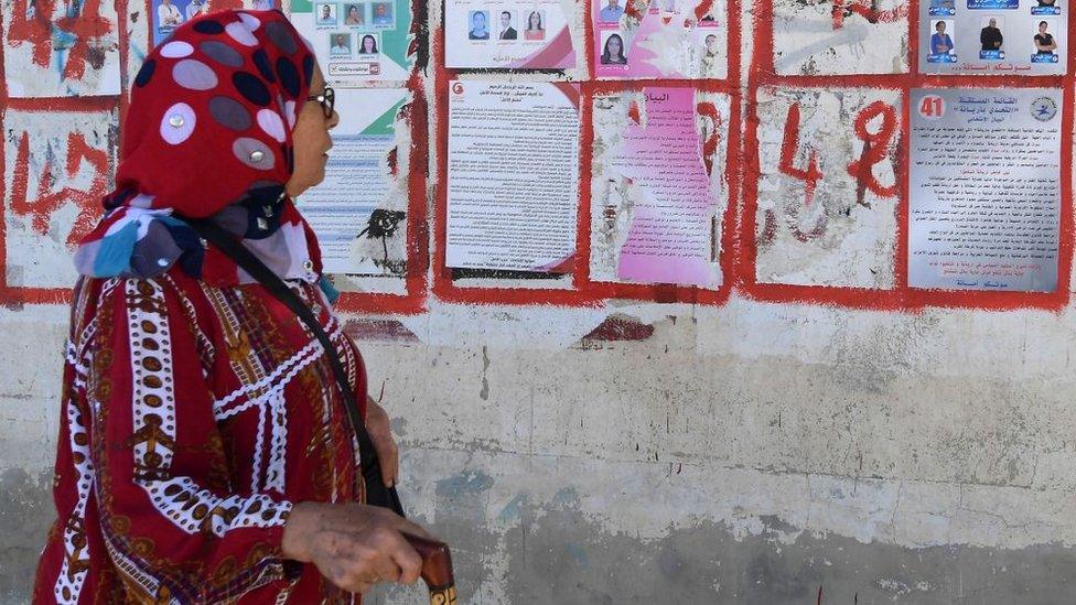 Woman walks past Tunisia election campaign posters