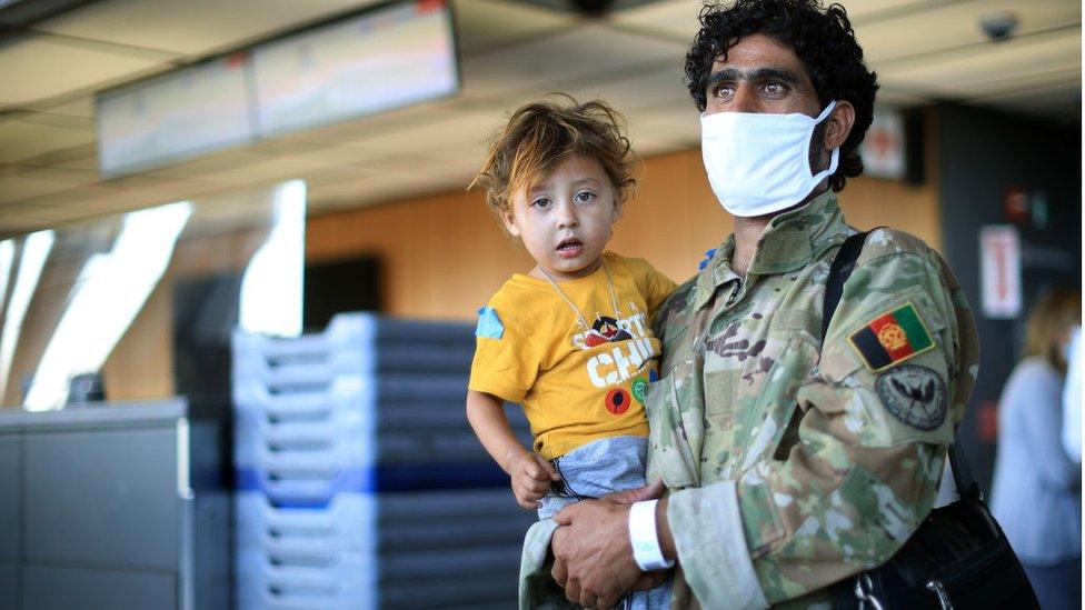 Two Afghan refugees, a man holding a child, arrive at Dulles airport