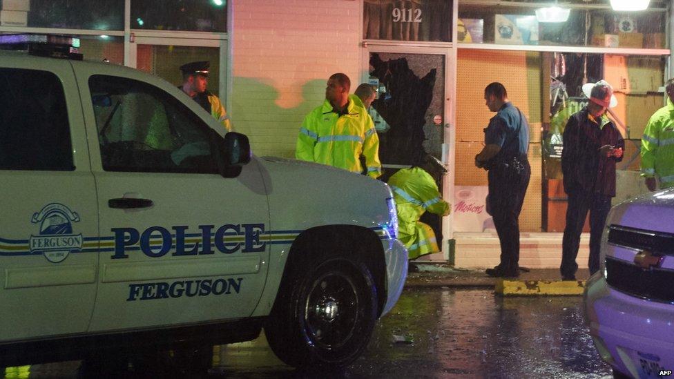 Police officers survey the damage to a local business on West Florissant Avenue in Ferguson, Missouri on August 9, 2015.